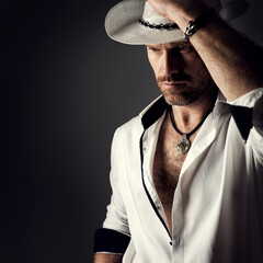 Cowboy in Hat. Handsome Bearded Man Fashion Portrait over Black Background. Sexy Brutal Men Model...