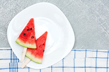 Watermelon slice on white plate and gray table background.