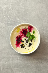 Cauliflower puree potato soup in round bowl on a gray background, top view. Vegetarian healthy food delivery concept