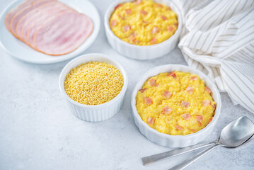 Cheesy millet with ham slices in a baking bowl