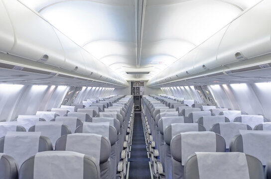 Commercial aircraft cabin with rows of seats down the aisle.