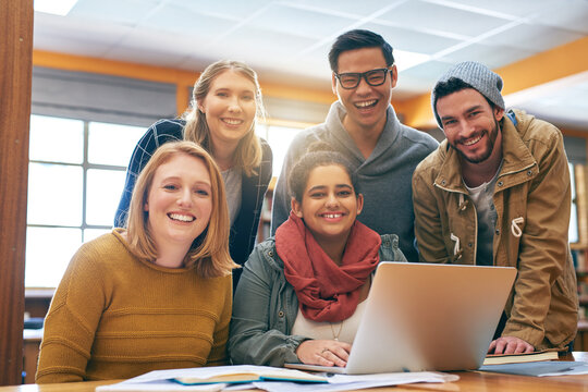 It Feels A Bit Better When Youre Studying Together. Portrait Of A Cheerful Young Group Of Students Working Together Using A Laptop To Study For Exams Inside Of A Library.