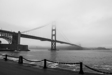 Grayscale shot of the Golden Gate Bridge in San Francisco, California with some parts covered in fog