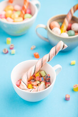 Heap of multicolored caramel candies in cups on blue background. side view, selective focus.