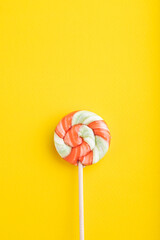 Single lollipop candy on yellow background. copy space, top view