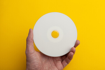 compact disc with a blank surface in hand on a yellow background