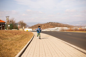 Obraz premium A five-year-old little Ukrainian boy rides an electric scooter in Most City, Czech Republic.