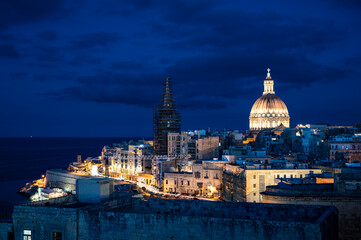 Panoramic view of illuminated at night Valletta old town and harbor in Valletta, Malta.