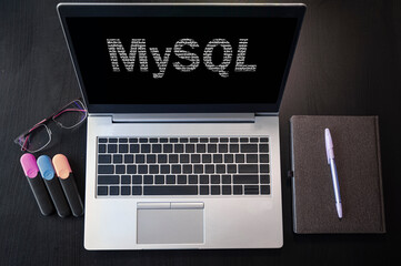 Top view of laptop with text MySQL. MySQL inscription on laptop screen and keyboard. Learn MySQL language, computer courses, training.