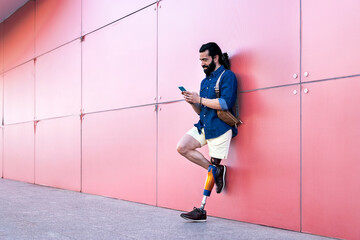 Man with artificial leg standing with smartphone in city