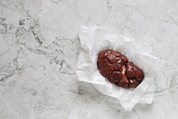 Raw beef kidneys ready to cook with vegetables and herbs on marble kitchen table. Flat layot, copy space.