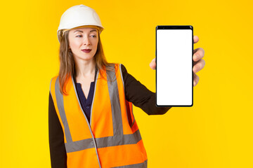 Great mobile ad. Woman Builder shows smartphone. Mobile phone with white screen. Mocap mobile phone. Template for advertising on construction theme. Builder on yellow. Gadget with empty space