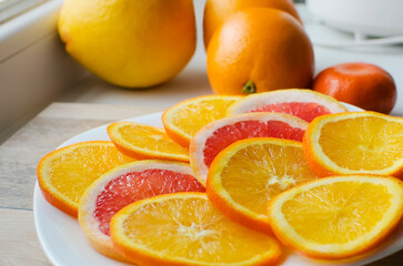 Slices, whole citruses, Tangerines, oranges, grapefruits are lying on a plate. Summer exotic tropical fruits. The concept of proper nutrition.