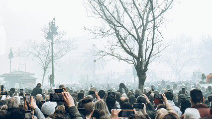 a crowd of people witness the mascleta of the fallas de valencia while recording it with their cell...