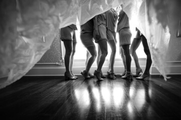 Grayscale shot of bridesmaids taken from under the wedding dress