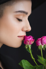 close up view of female profile near pink tiny roses isolated on black.