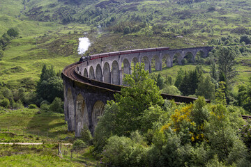 Steaming train on the Glenfinnan train viaduct in Scotland, UK