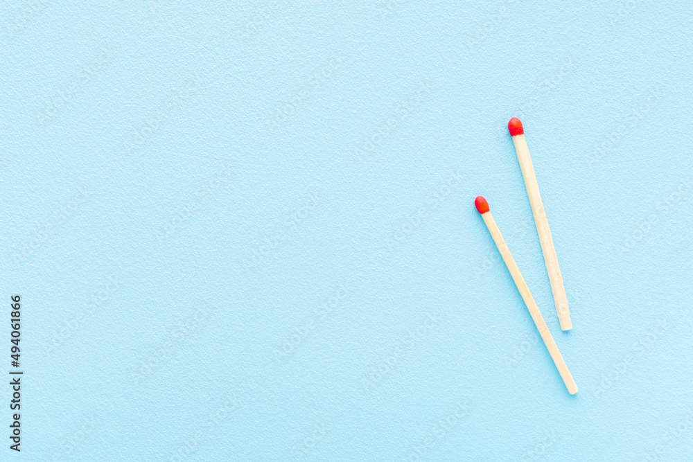 Wall mural two new match sticks on light blue table background. pastel color. closeup. empty place for text. to