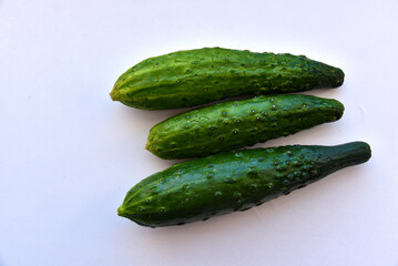 Three green fresh cucumbers on a white background