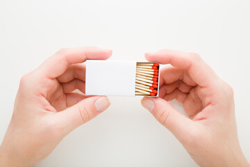 Young adult woman hand holding and showing opened box of match sticks on white background. Closeup....