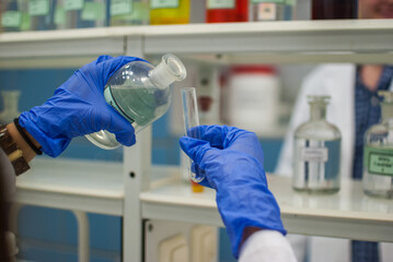 Laboratory worker with gloves pouring a liquid into a tube