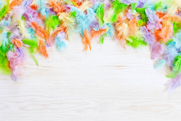 Top view of colored Easter feathers on white wooden background. Easter concept