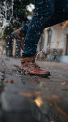 Vertical shot of a male stepping into a splashing water in the street