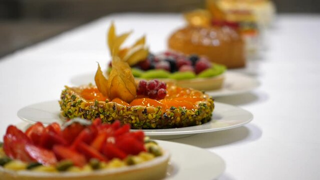 Crostata ai frutti di bosco con crema, fragole, lamponi, ribes, more, kiwi.
Piatto di lavagna nera con torte ai frutti di bosco e zucchero a velo. Pasticceria professionale.