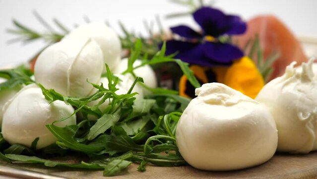 tagliere in legno con mozzarella, burrata, prosciutto e rughetta.

Piatto girevole con formaggi e salumi tipici italiani. cucina italiana