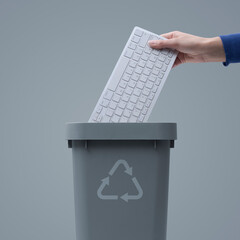 Woman putting a computer keyboard in the trash bin