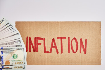 World economic crisis and inflation concept, Cardboard sheet with word inflation and us dollar banknotes, Rising prices for consumer goods and services