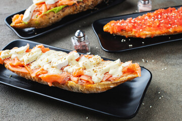 Traditional Spanish breakfast. Tostada with different toppings on a dark background