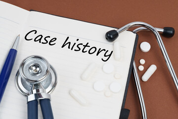 On a brown surface lie pills, a pen, a stethoscope and a notebook with the inscription - Case...