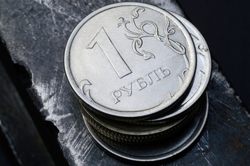 a stack of Russian rubles lies on a scratched metal surface. translation of the text on the coin:...