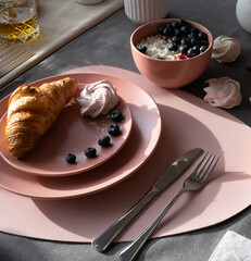 Croissants on a pink plate, sprinkled with powdered.decorated with berries.