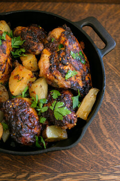 Roast chicken in cast iron skillet with potatoes and fresh herbs