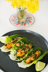 Roasted chicken in lettuce wraps with peanut sauce and fresh herbs on plate