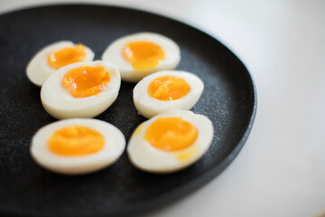 Three hard boiled eggs with gooey yolks cut open on black plate