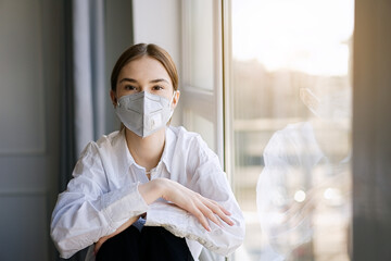 COVID-19 Pandemic Coronavirus. Young girl home isolation quarantine wearing face mask ffp2...