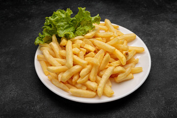 Fried potatoes with lettuce, on a black background