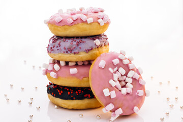 Shot of five sweet doughnuts stacked on top of each other in the form of a tower. Tasty delicious sweet do nut with colorful sprinkles on white background