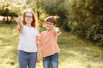 Child in glasses show thumbs up outdoor.
