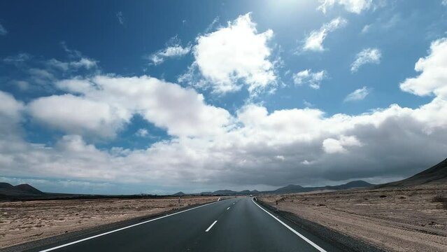 Dramatic sky landscape with long straight road and fast moving movement from car or van vehicle. Cloudy sky and mountains at horizon. Beautiful sunny weather and blue sky. Concept of travel and drive