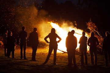 People standing watching a bonfire in the park in the dark night