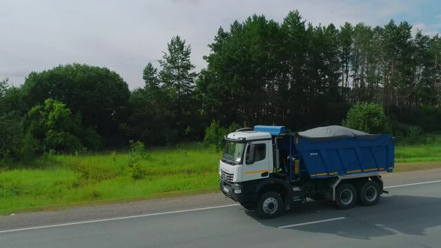 Dump truck driving on highway. Scene. Top view of dump truck on highway in summer. Truckers and dump trucks on country road