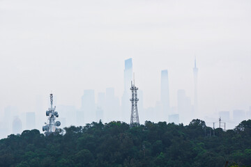 Beautiful shot of many trees in the background of a faded Guangzhou cityscape.