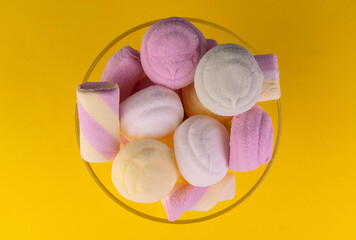 Colored marshmallows in a vase on a yellow background. Flat lay.