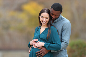 Happy interracial couple looking at pregnant belly