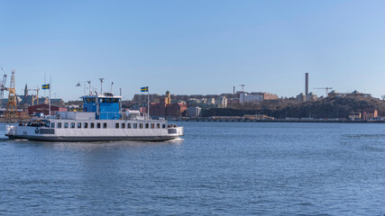 Fototapeta na wymiar Panorama view a commuting boat Djurgårdsfärja leaving a jetty for the old town Gamla Stan from the island Djurgården a sunny spring day in Stockholm