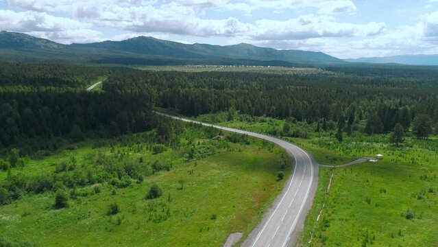Top view of beautiful highway with forest and greenery on background of mountains. Scene. Landscape of road on background of green forest and mountains in summer